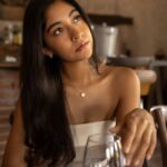 Young woman with long hair sits thoughtfully in a rustic cafe, creating a warm, relaxed atmosphere.